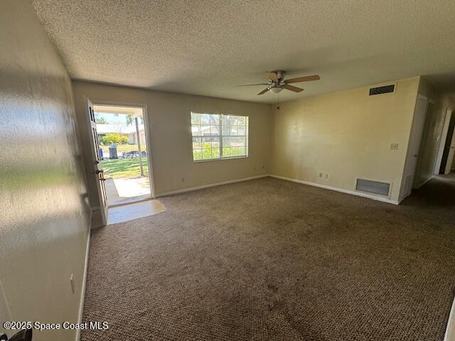 interior space featuring visible vents, carpet, a ceiling fan, and a textured ceiling