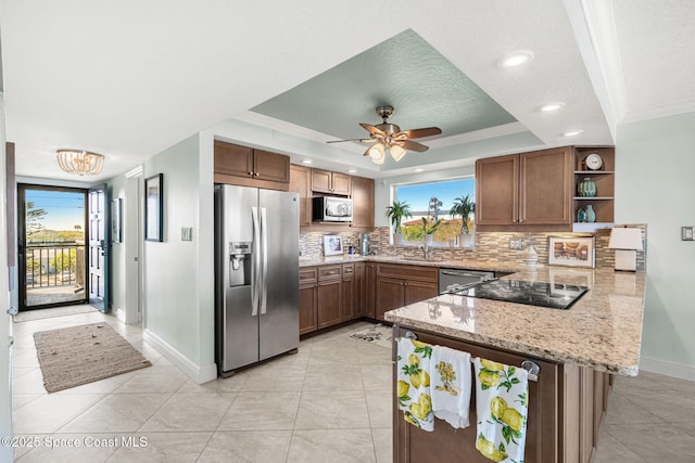 kitchen with stainless steel appliances, tasteful backsplash, a tray ceiling, light stone countertops, and kitchen peninsula