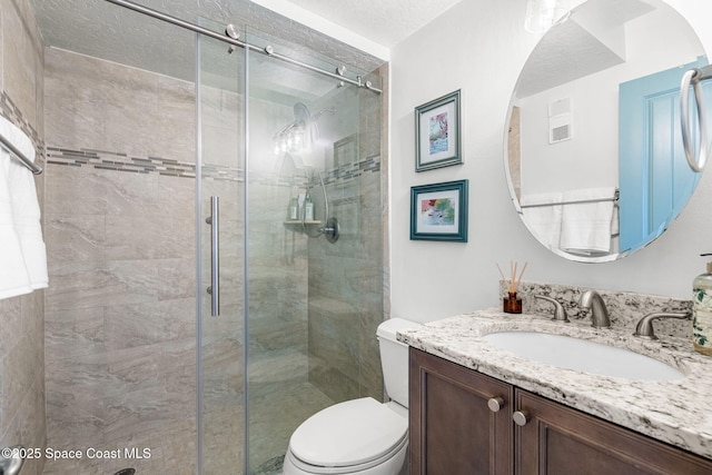 bathroom with vanity, a textured ceiling, toilet, and walk in shower