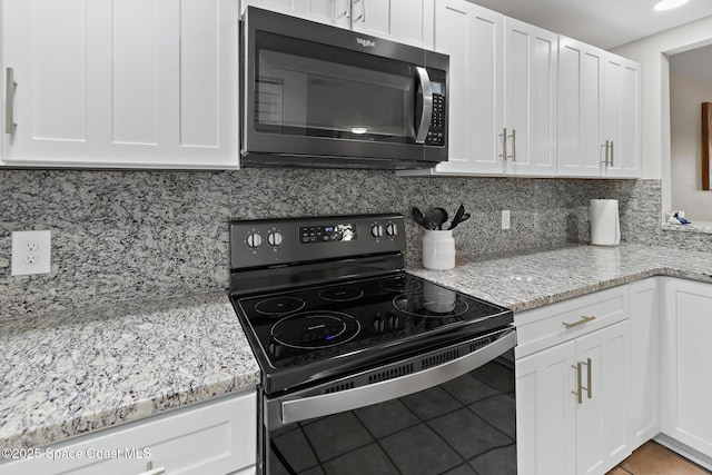 kitchen with tasteful backsplash, white cabinetry, light tile patterned floors, black range with electric stovetop, and light stone countertops