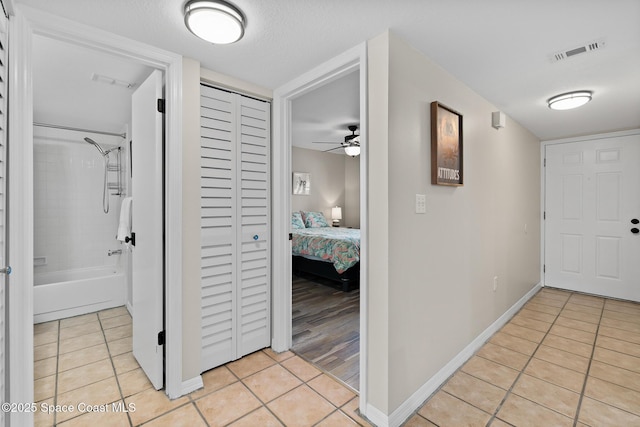 hallway featuring light tile patterned floors and a textured ceiling