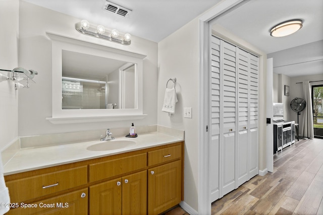 bathroom featuring vanity, wood-type flooring, and walk in shower