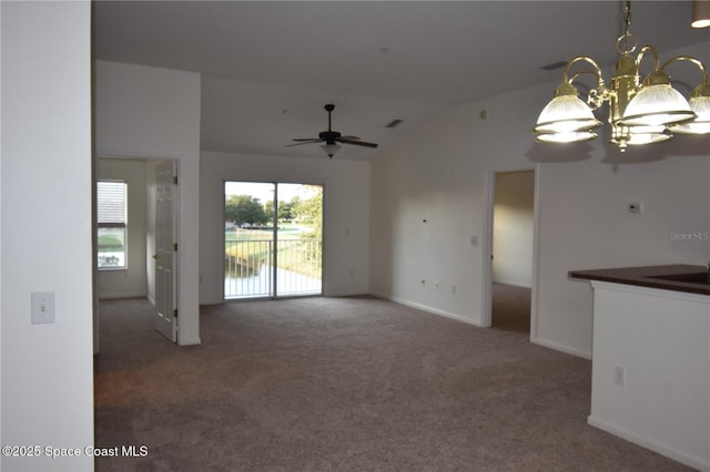 unfurnished living room featuring lofted ceiling, ceiling fan with notable chandelier, and dark carpet