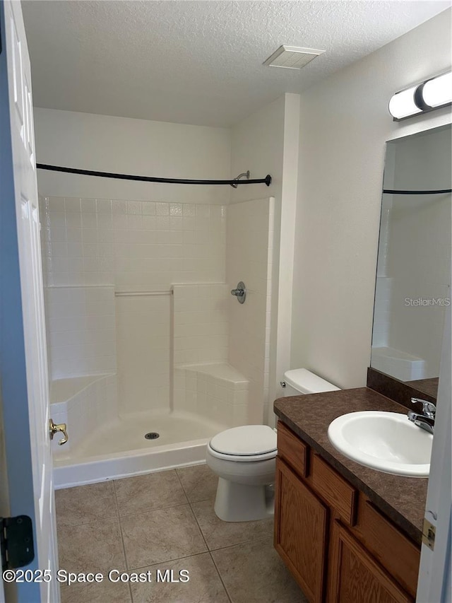 bathroom with vanity, a textured ceiling, tile patterned floors, toilet, and walk in shower