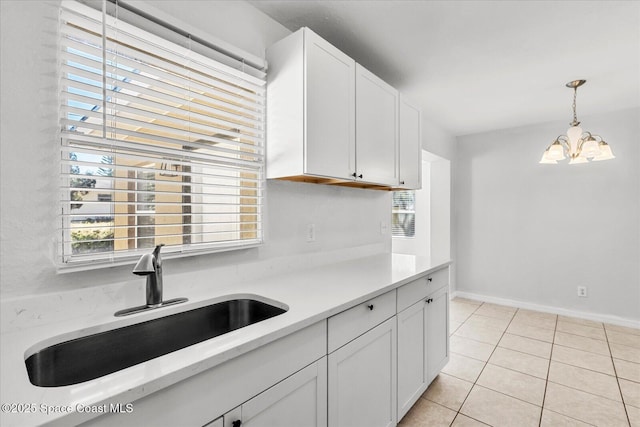 kitchen featuring sink, decorative light fixtures, light tile patterned floors, plenty of natural light, and white cabinets