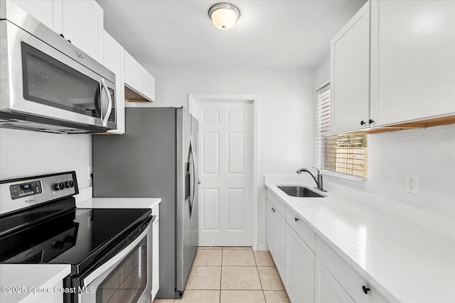 kitchen with white cabinetry, stainless steel appliances, light tile patterned flooring, and sink