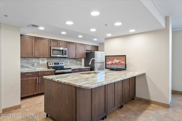 kitchen featuring sink, stainless steel appliances, light stone counters, decorative backsplash, and kitchen peninsula