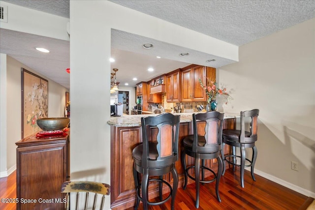 bar featuring a textured ceiling, dark hardwood / wood-style flooring, and decorative backsplash