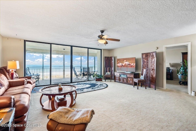 living room with ceiling fan, floor to ceiling windows, a textured ceiling, and carpet flooring