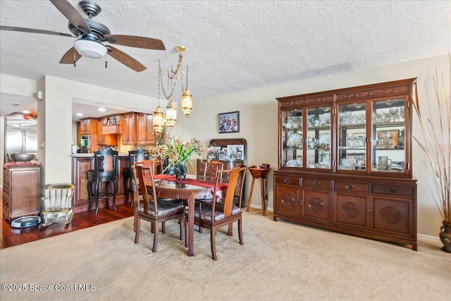 carpeted dining space with ceiling fan and a textured ceiling