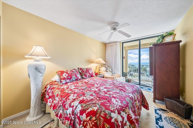 carpeted bedroom featuring floor to ceiling windows, access to outside, ceiling fan, and a textured ceiling