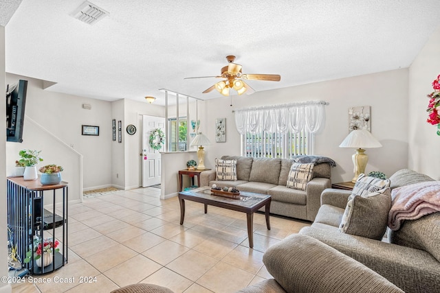 living room featuring light tile patterned floors, a textured ceiling, and ceiling fan