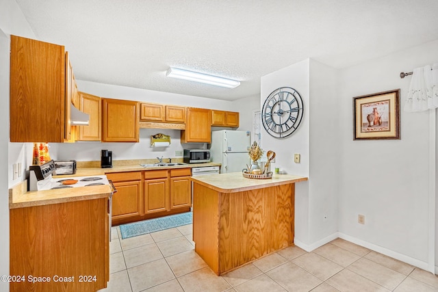 kitchen featuring sink, light tile patterned floors, white appliances, a textured ceiling, and kitchen peninsula