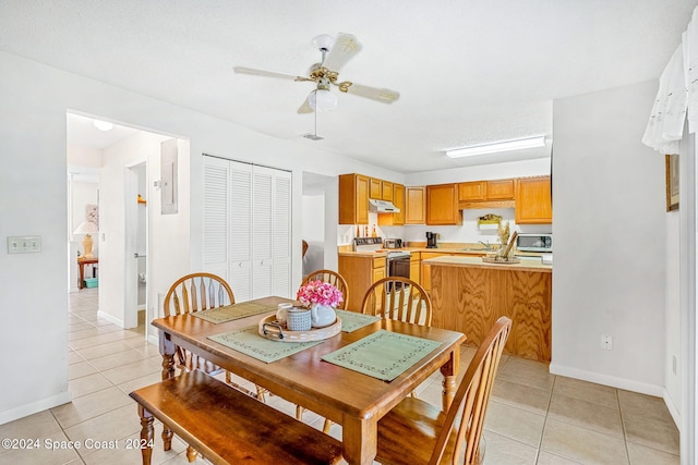 tiled dining space with a textured ceiling and ceiling fan