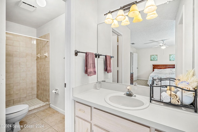 bathroom featuring tiled shower, tile patterned floors, toilet, a textured ceiling, and vanity