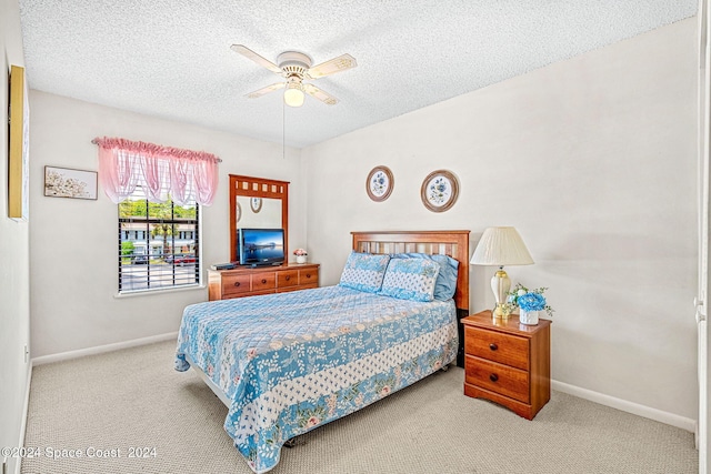 bedroom with ceiling fan, light colored carpet, and a textured ceiling