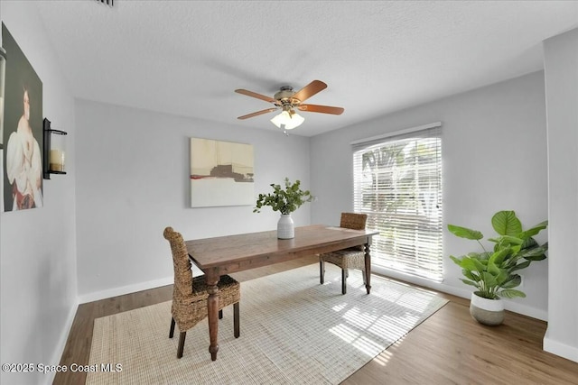 dining space with hardwood / wood-style flooring, a textured ceiling, and ceiling fan