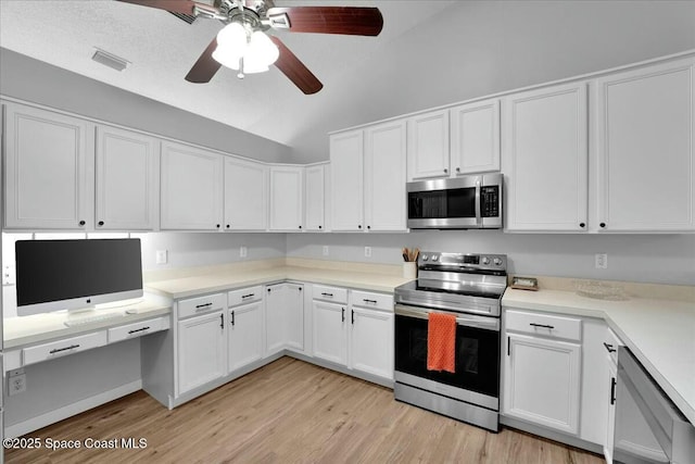 kitchen with built in desk, white cabinetry, ceiling fan, stainless steel appliances, and light wood-type flooring