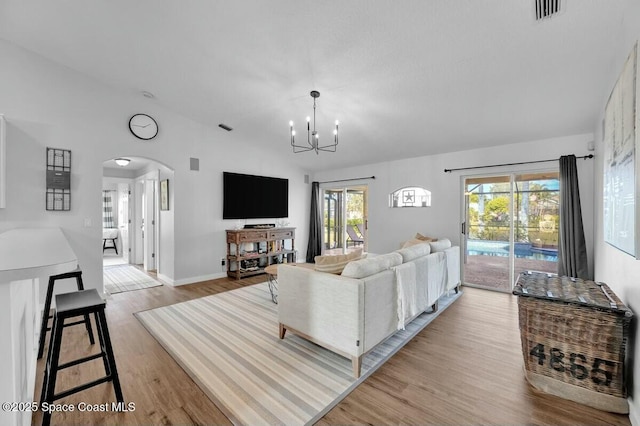 living room with a chandelier, a wealth of natural light, and light wood-type flooring