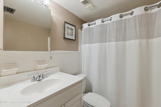 bathroom with tile walls, vanity, and toilet