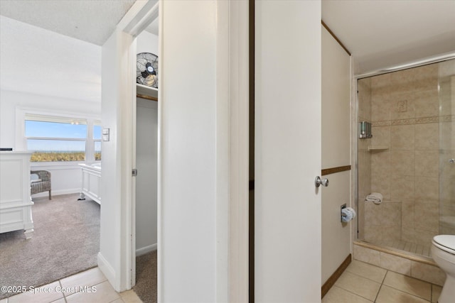 bathroom with tile patterned flooring, a shower with door, and toilet