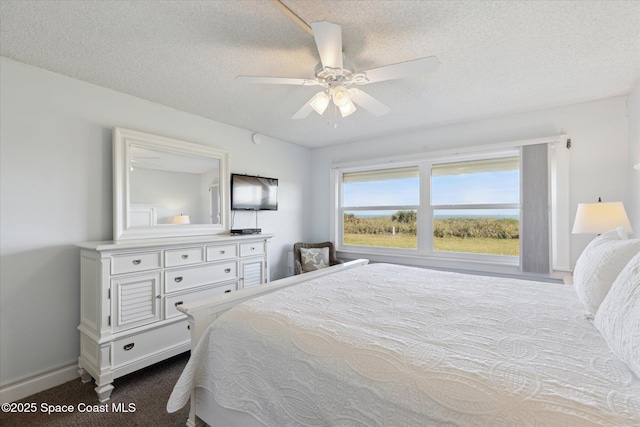 carpeted bedroom featuring ceiling fan and a textured ceiling