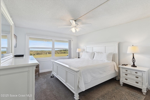 bedroom featuring ceiling fan, a textured ceiling, and dark colored carpet