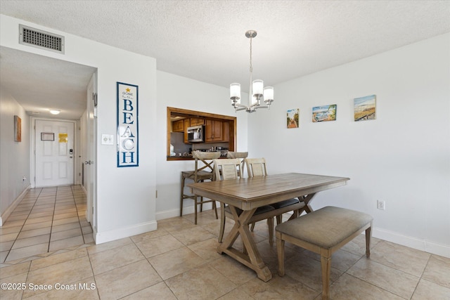 dining space with a notable chandelier, light tile patterned floors, and a textured ceiling