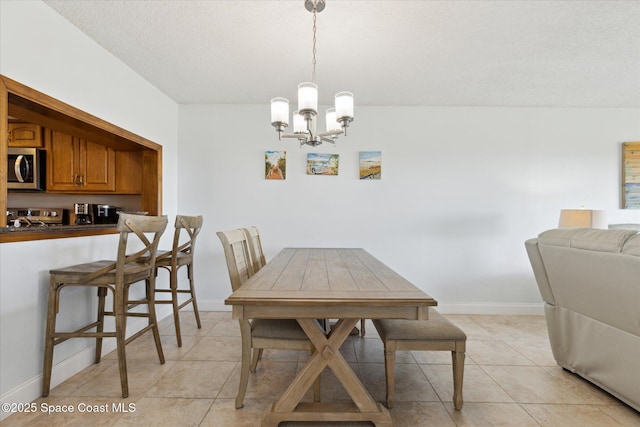 dining area with light tile patterned floors, a textured ceiling, and a chandelier