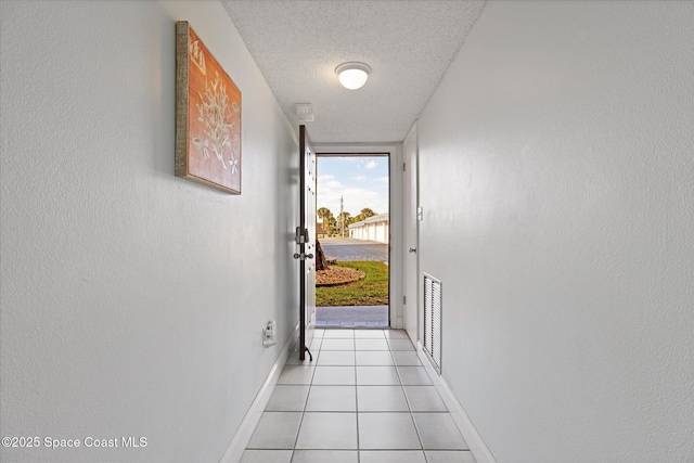 doorway featuring light tile patterned floors and a textured ceiling