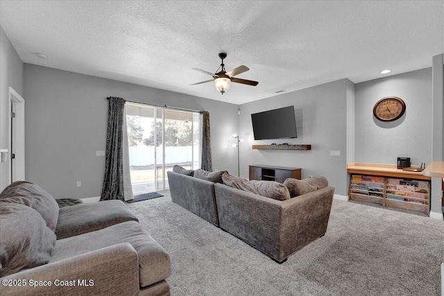 living room featuring ceiling fan, light carpet, and a textured ceiling