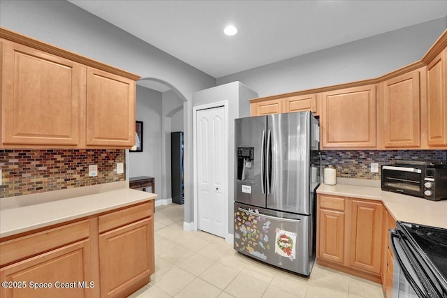 kitchen featuring tasteful backsplash, light tile patterned flooring, stainless steel fridge, and electric range