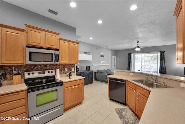 kitchen featuring tasteful backsplash, sink, stainless steel appliances, light brown cabinets, and a textured ceiling