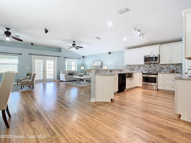 kitchen featuring french doors, a kitchen bar, light stone counters, stainless steel appliances, and white cabinets