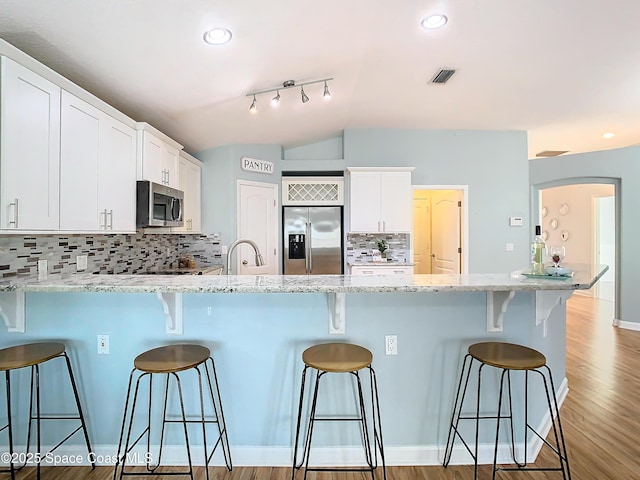 kitchen featuring stainless steel appliances, white cabinetry, and a kitchen breakfast bar