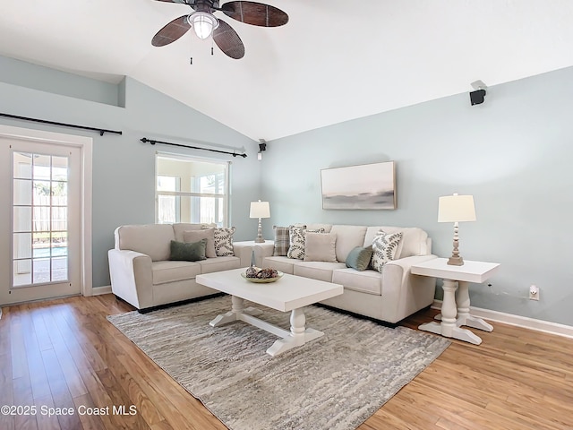 living room with vaulted ceiling, a healthy amount of sunlight, and light wood-type flooring