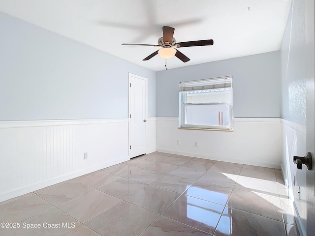 tiled empty room featuring ceiling fan