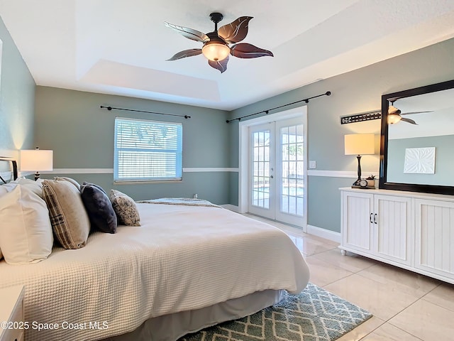 tiled bedroom with french doors, ceiling fan, a raised ceiling, and access to outside