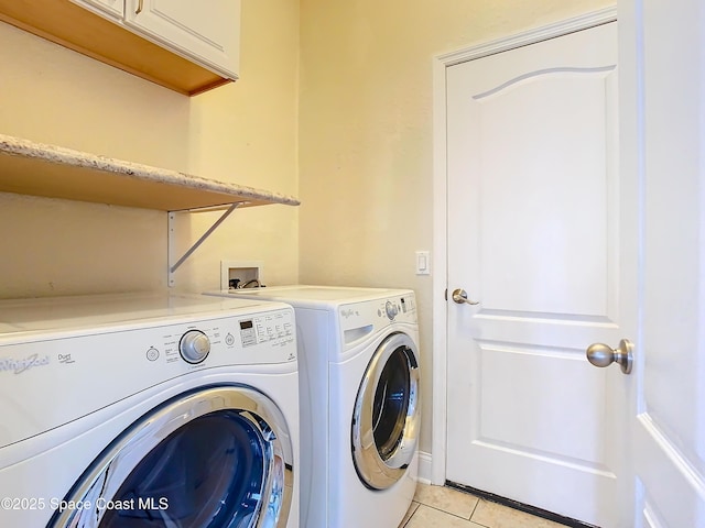 washroom featuring light tile patterned floors, washing machine and dryer, and cabinets