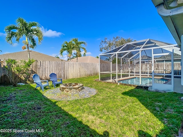 view of yard featuring a fenced in pool, glass enclosure, and a fire pit