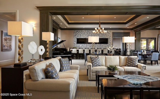 living room featuring ornamental molding, a raised ceiling, and a notable chandelier
