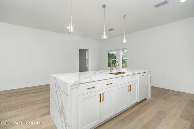 kitchen featuring sink, a kitchen island with sink, white dishwasher, and white cabinets