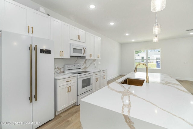 kitchen with sink, white cabinetry, light stone counters, pendant lighting, and white appliances