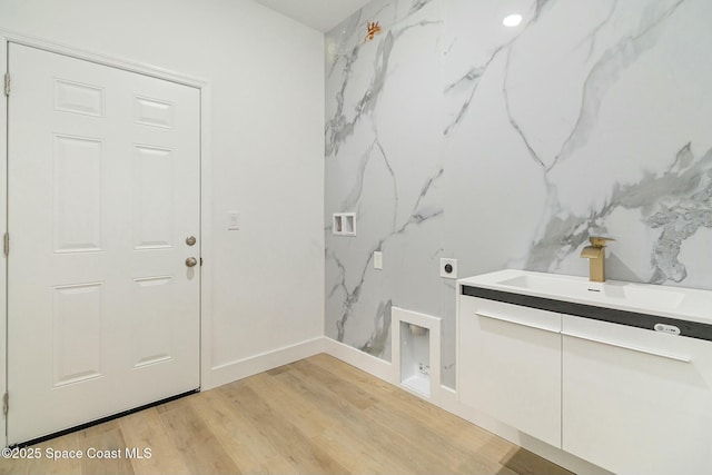 washroom featuring electric dryer hookup, sink, and light hardwood / wood-style floors