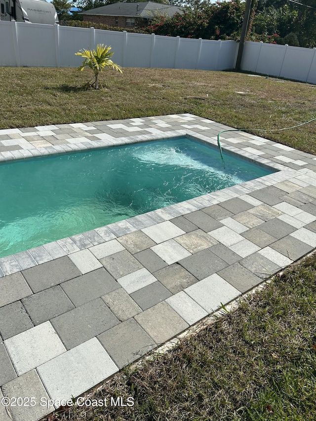 view of pool with a patio and a lawn