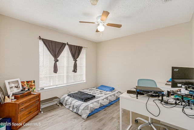 bedroom featuring a textured ceiling, light hardwood / wood-style flooring, and ceiling fan