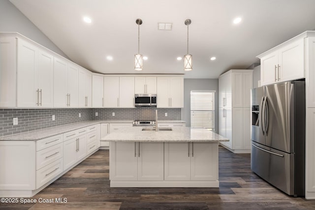 kitchen featuring appliances with stainless steel finishes, a kitchen island with sink, light stone counters, white cabinets, and decorative light fixtures