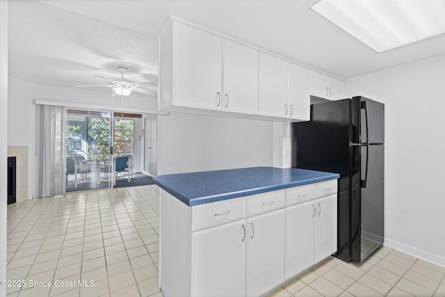 kitchen featuring white cabinetry, light tile patterned floors, and black fridge