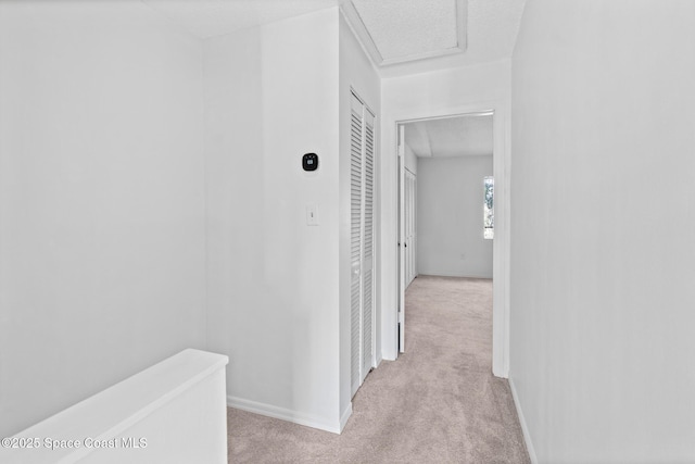 hallway with light carpet and a textured ceiling