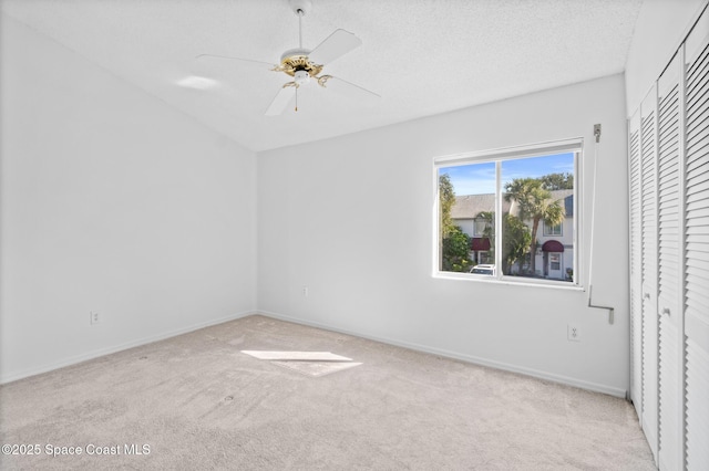 unfurnished bedroom with light colored carpet, a textured ceiling, ceiling fan, and a closet